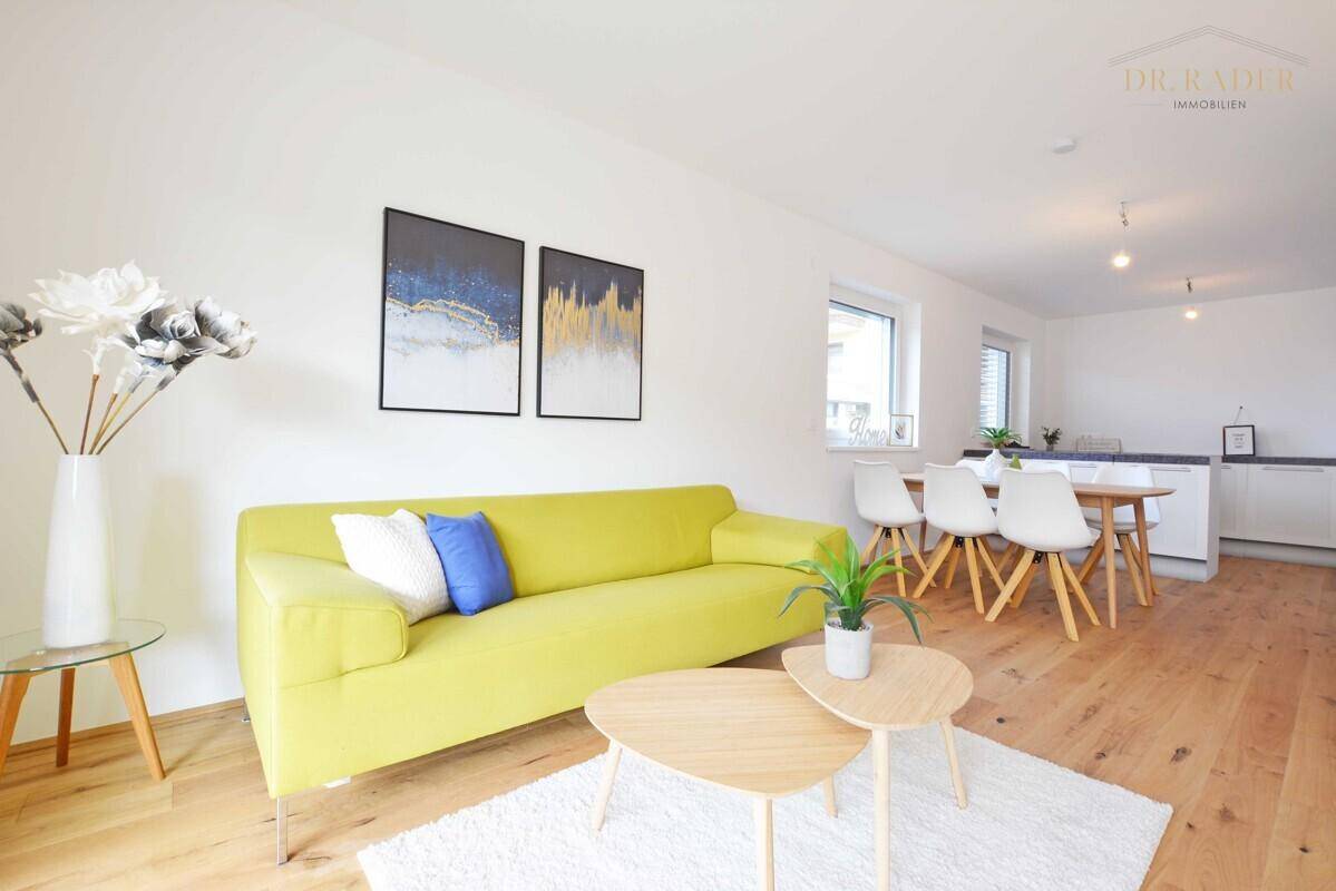 Lichtdurchfluteter offener Wohn-Essbereich mit gelbem Sofa, Holzboden und moderner Küchenzeile.