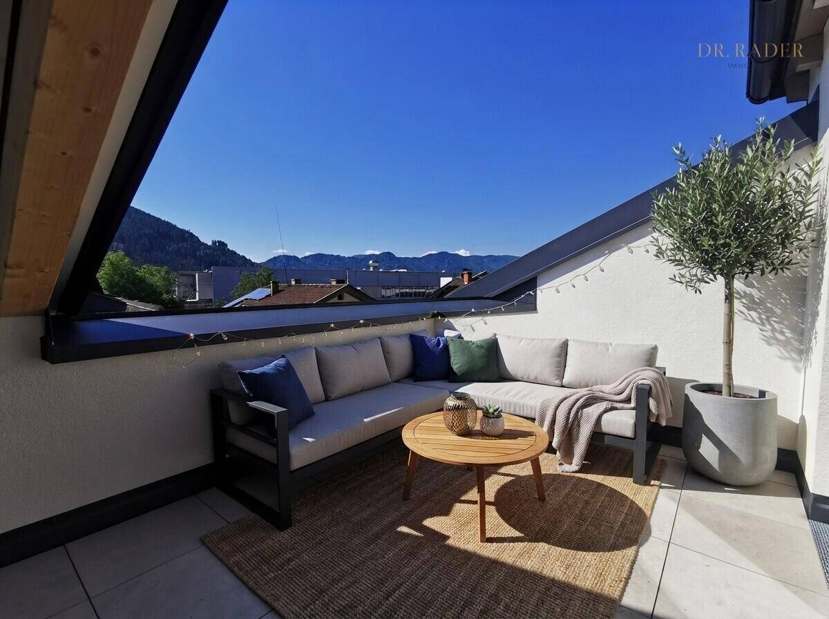 Sonnige Dachterrasse mit bequemen Outdoor-Möbeln und weitem Bergblick.