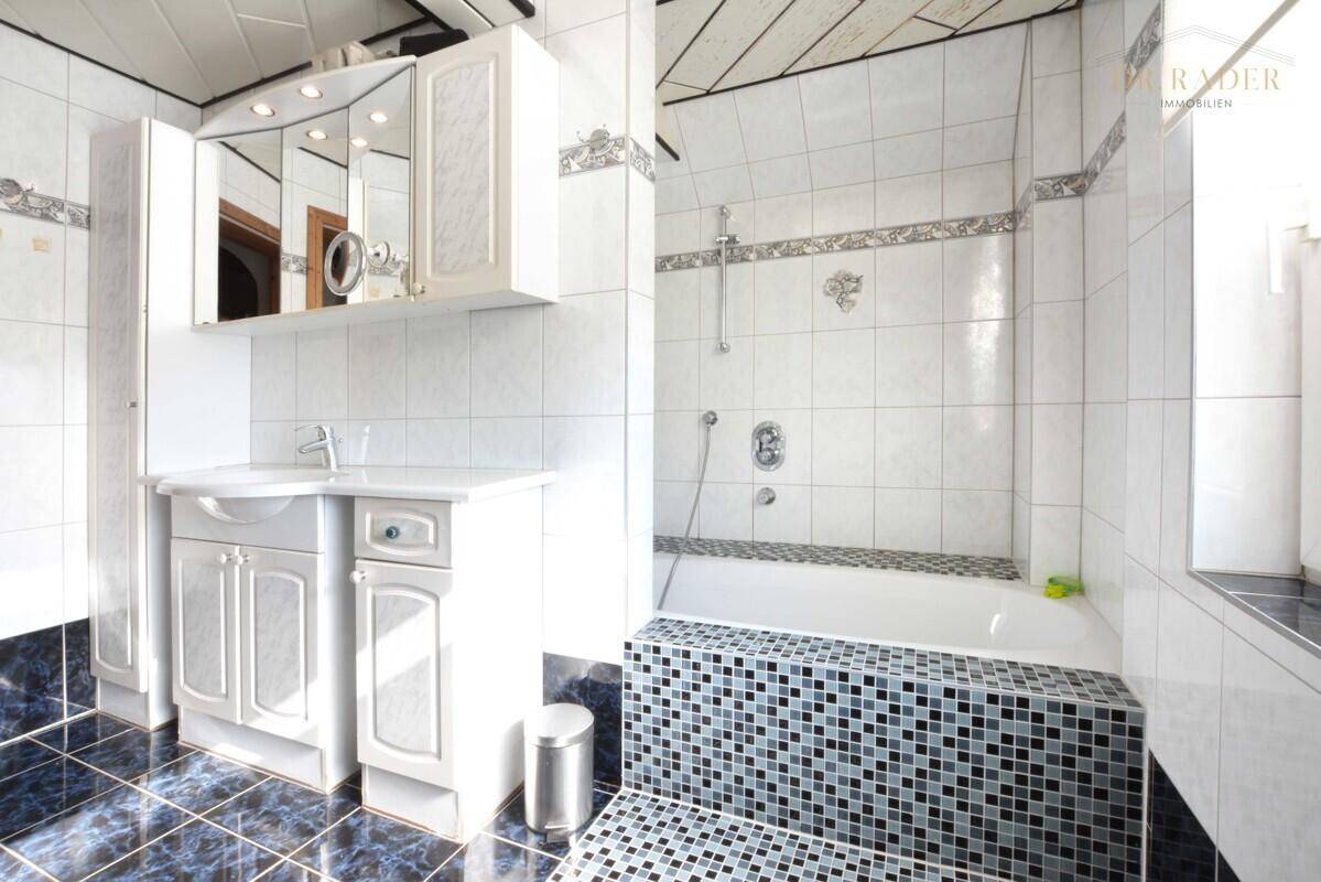 Badezimmer mit Badewanne, Waschbecken und weiß-blauen Fliesen.