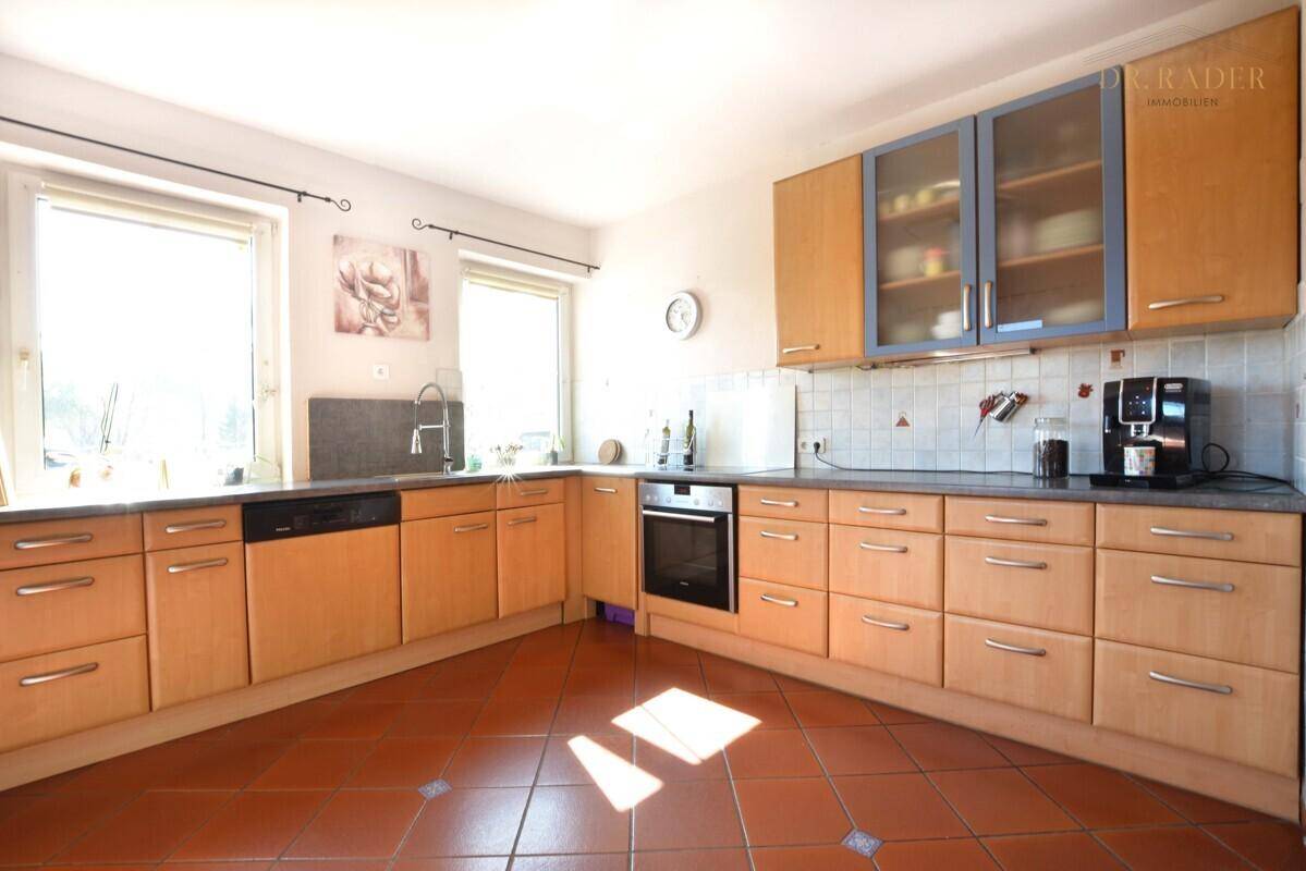 Funktionale Küche mit Holzfronten, Einbaugeräten und Terrakottafliesen.