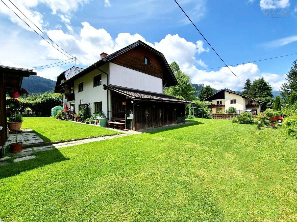 Großer, gepflegter Garten mit Rasenfläche und Blick auf die Berge.