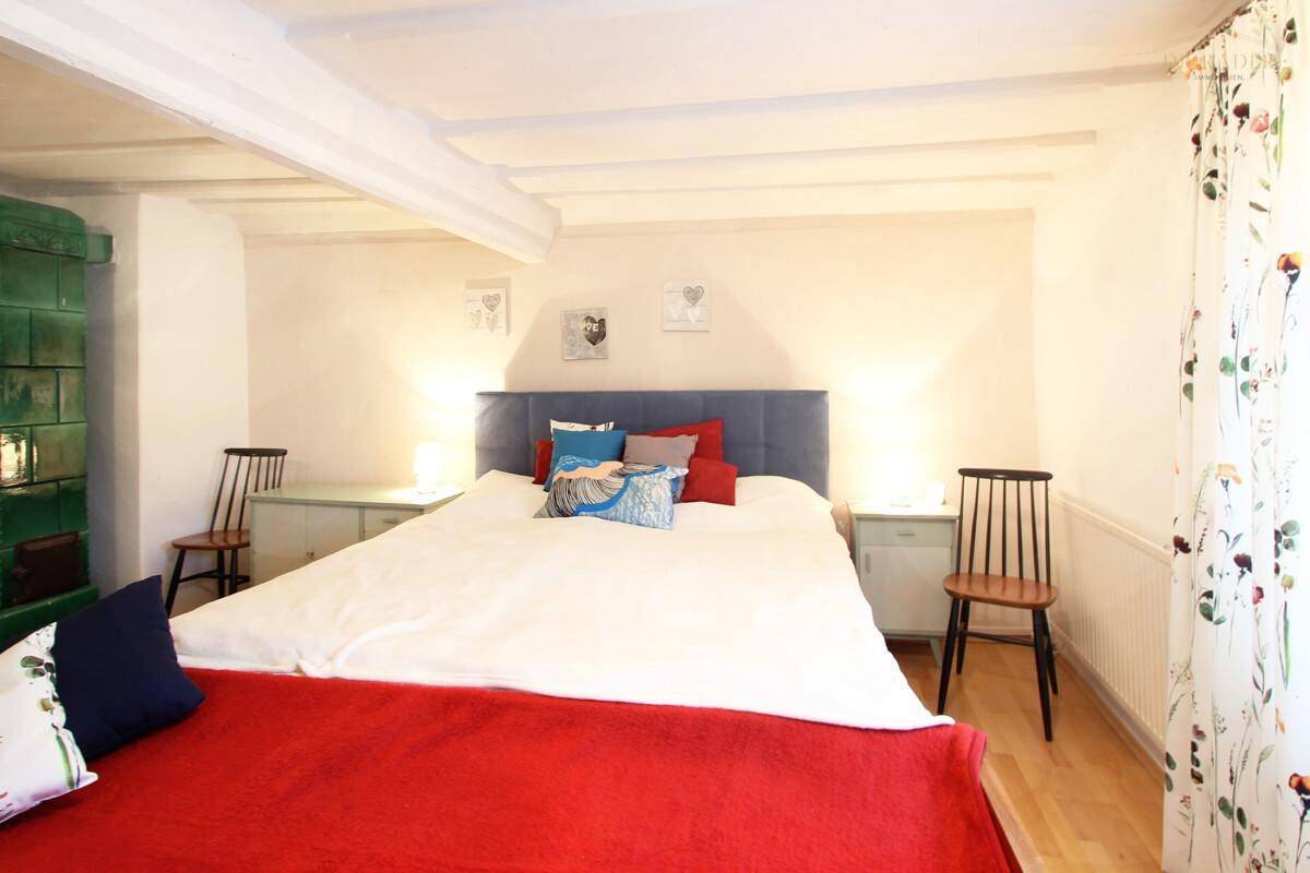 Schlafzimmer mit Doppelbett und traditionellem grünem Kachelofen.
