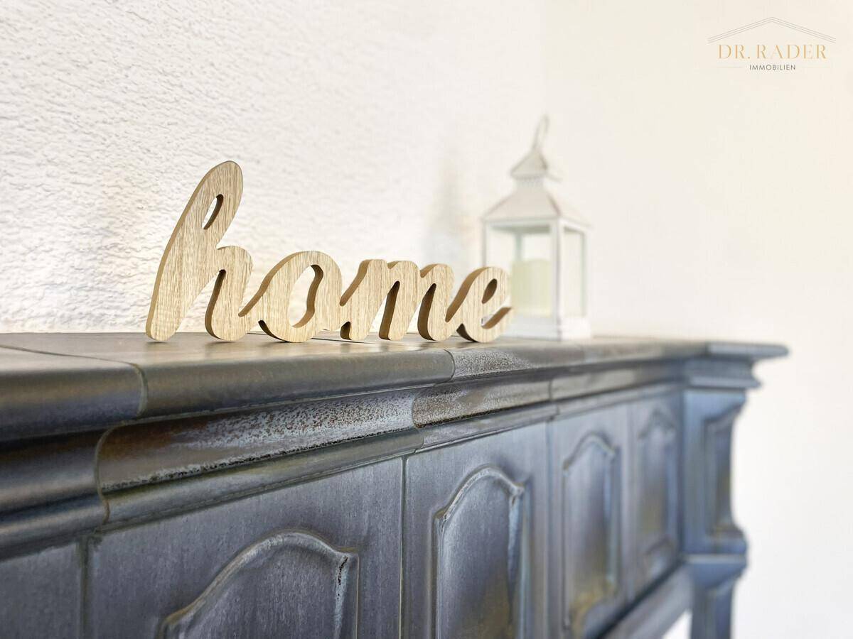 Detailaufnahme des Kaminsims mit dekorativer "Home"-Schrift und Laterne im Wohnzimmer.