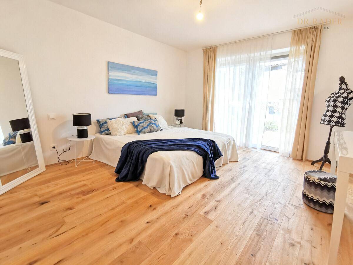 Geräumiges Schlafzimmer mit Doppelbett, Holzboden und direktem Zugang zu einem Außenbereich.