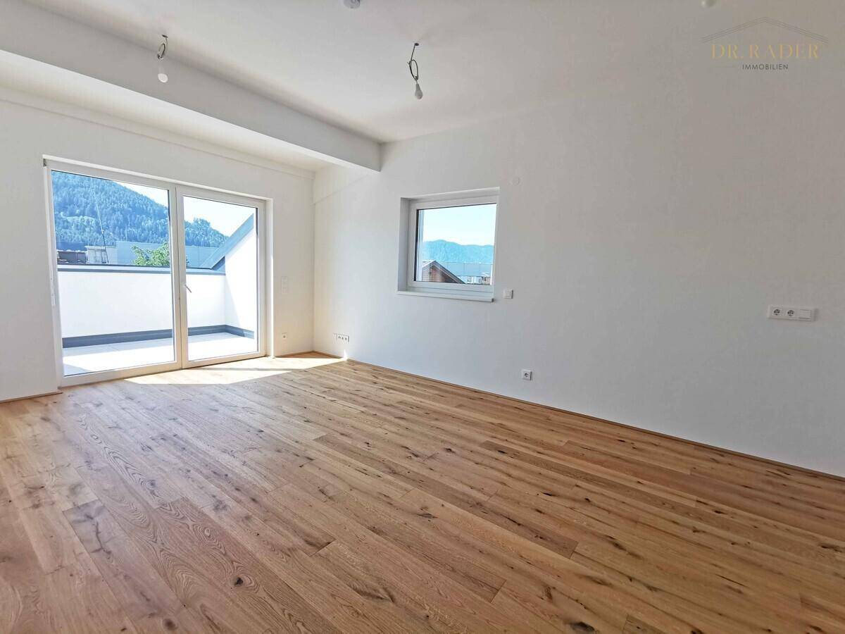 Geräumiger Raum mit Holzboden, viel Tageslicht und Zugang zu einer Terrasse mit Bergblick.