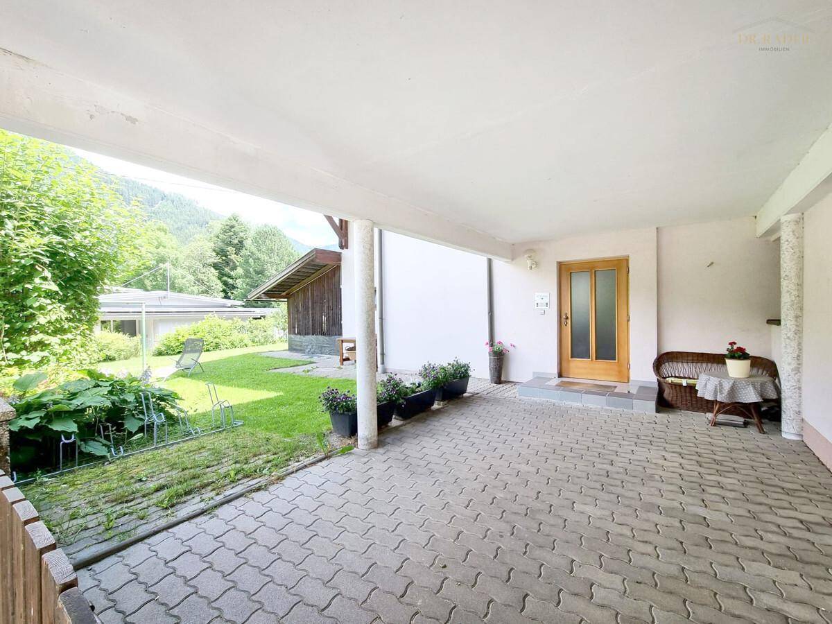 Überdachter Carport-Bereich mit Zugang zum Haus und Blick in den Garten.