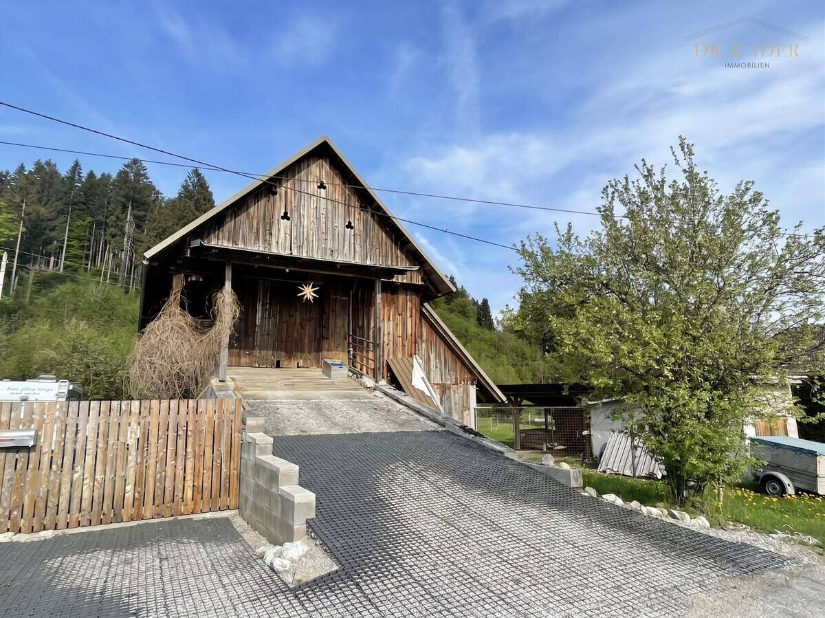 Rustikales Holzgebäude mit Zufahrt und ländlichem Charme, umgeben von Natur.