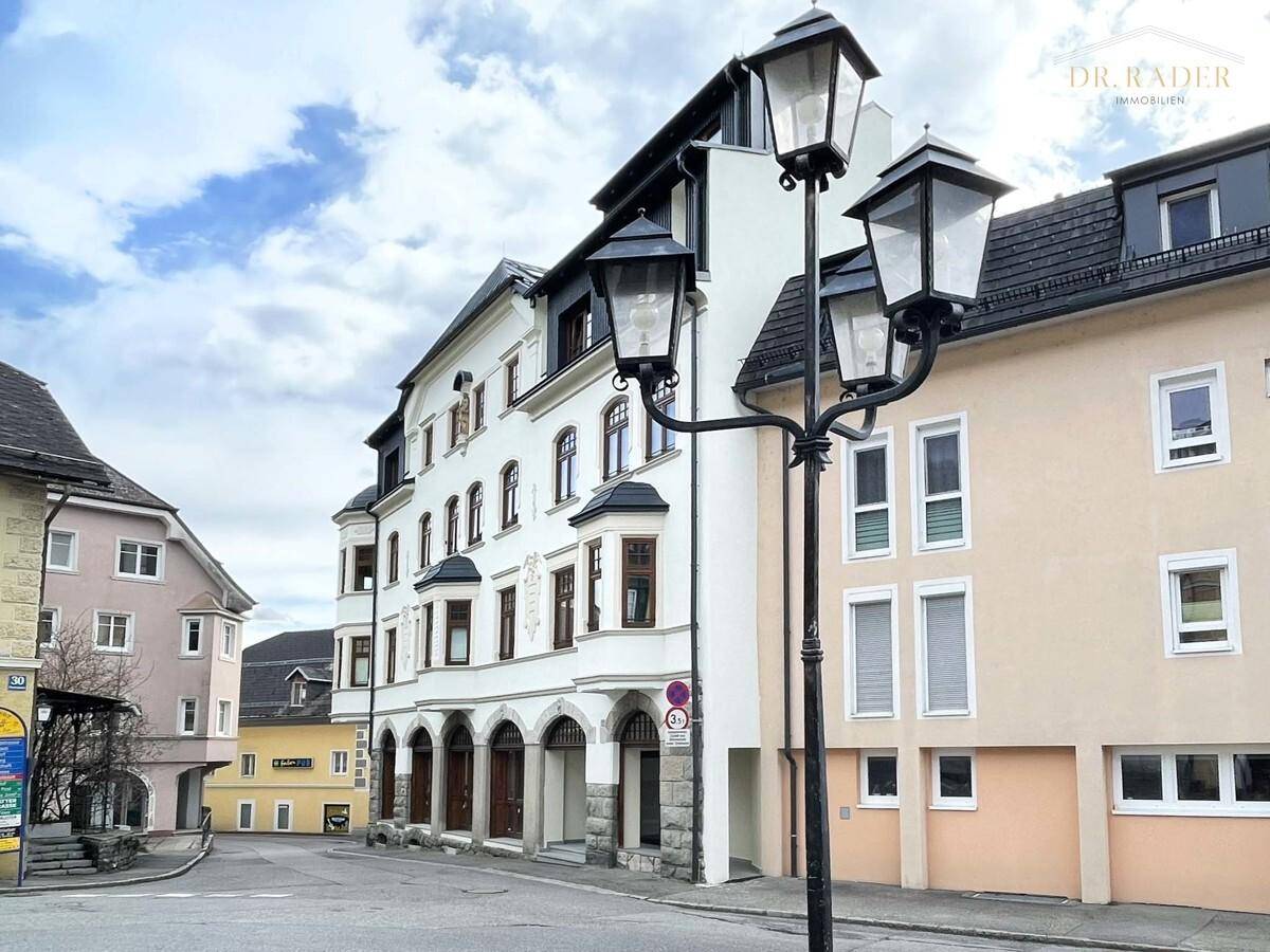 Historisches Gebäude mit traditioneller Architektur und Bogenfenstern an einer belebten Straße.