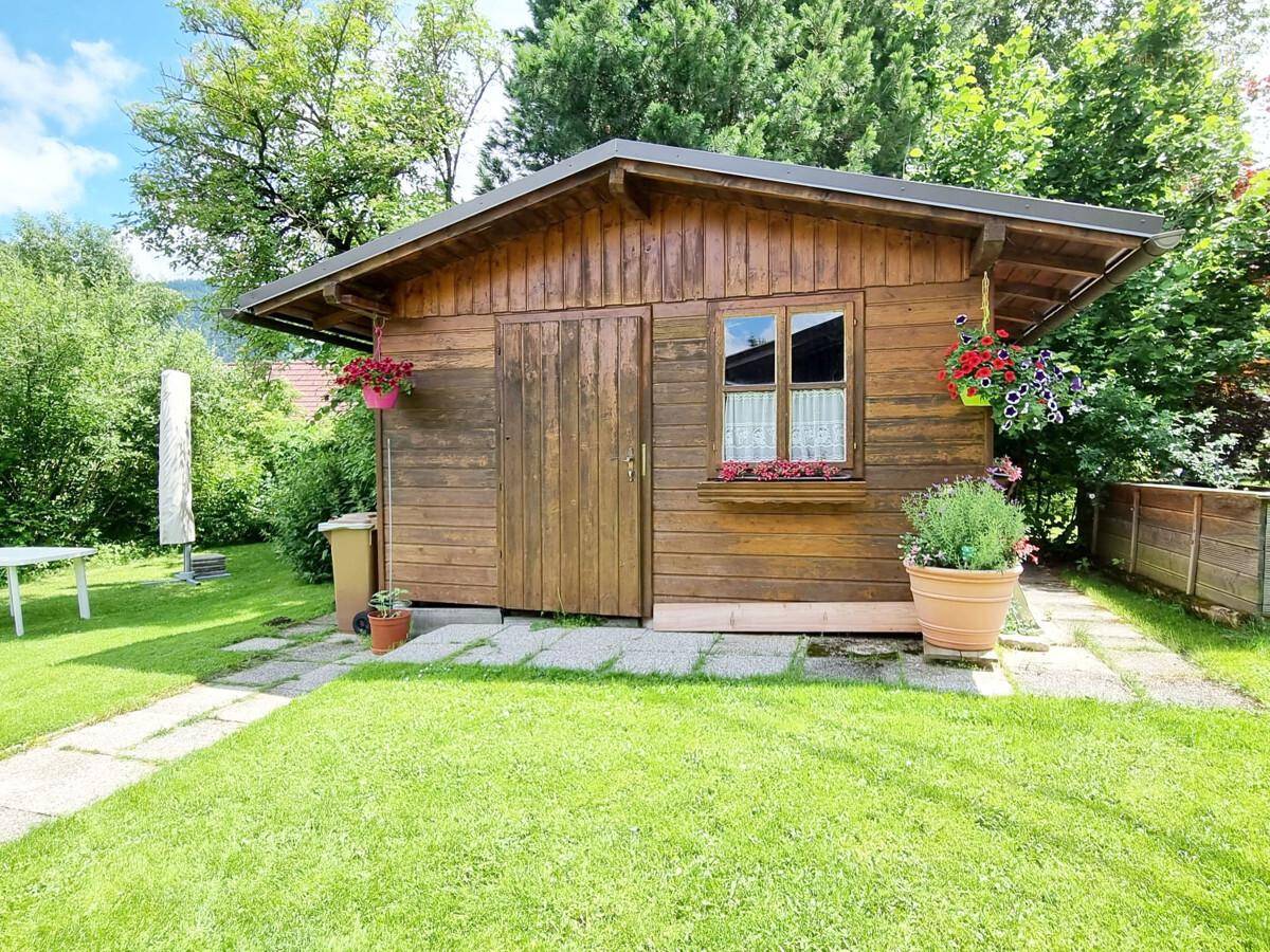 Rustikales Gartenhaus aus Holz mit Blumenkästen im grünen Garten.