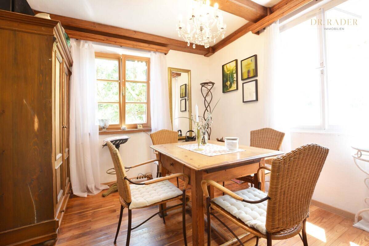 Heller Essbereich mit traditionellen Holzmöbeln, Korbstühlen und großem Fenster.