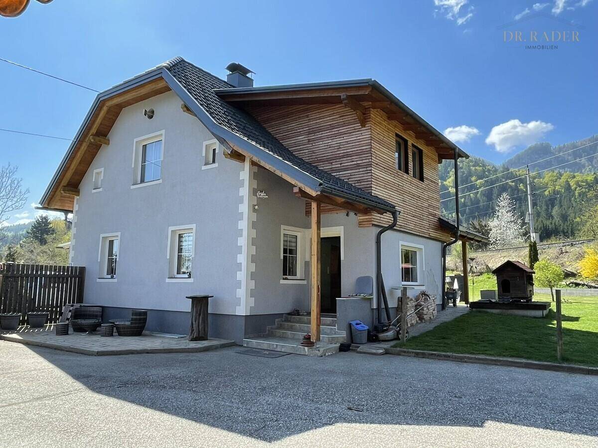 Charmantes Einfamilienhaus mit Holzverkleidung und traditionellem Satteldach in ländlicher Umgebung.