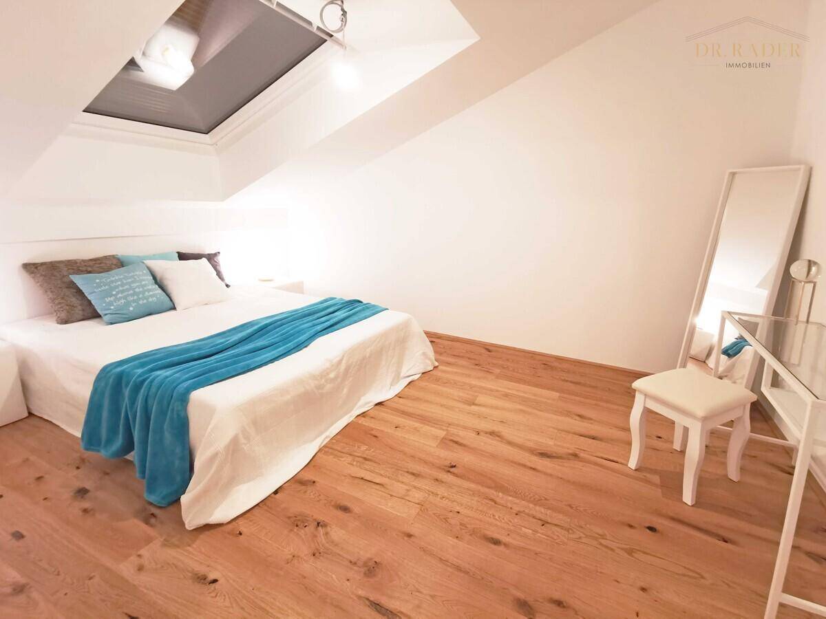 Gemütliches Schlafzimmer im Dachgeschoss mit Holzboden, großem Bett und viel natürlichem Licht.