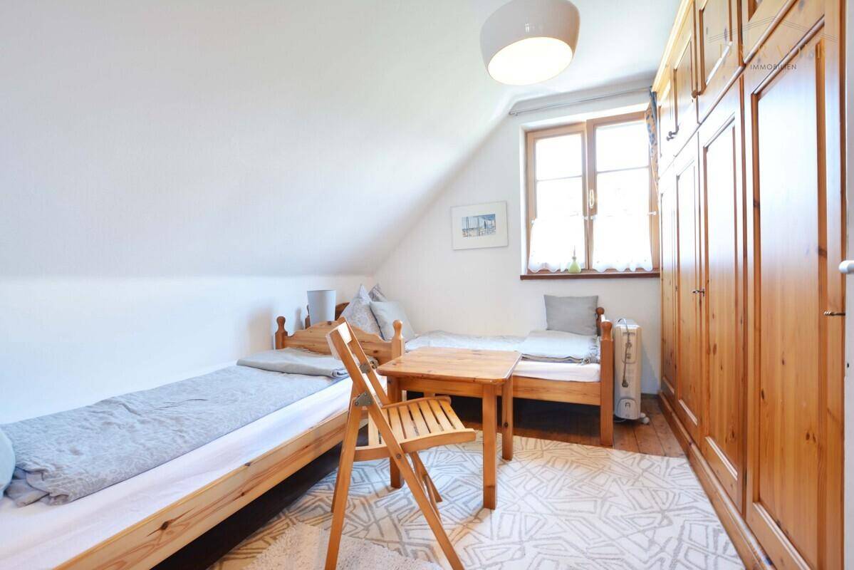 Kinder- oder Gästezimmer im Dachgeschoss mit zwei Einzelbetten und Holzschrank.