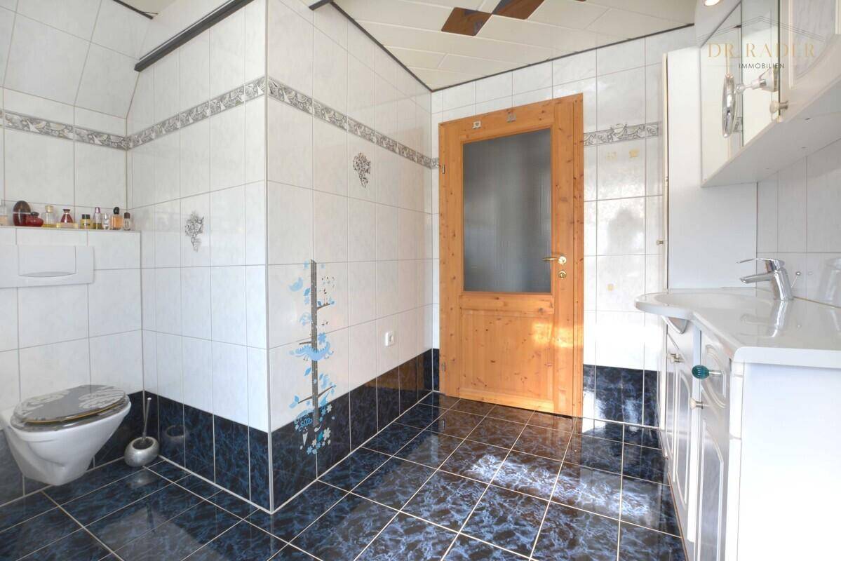 Badezimmer mit WC, Waschbecken und blauen sowie weißen Fliesen.