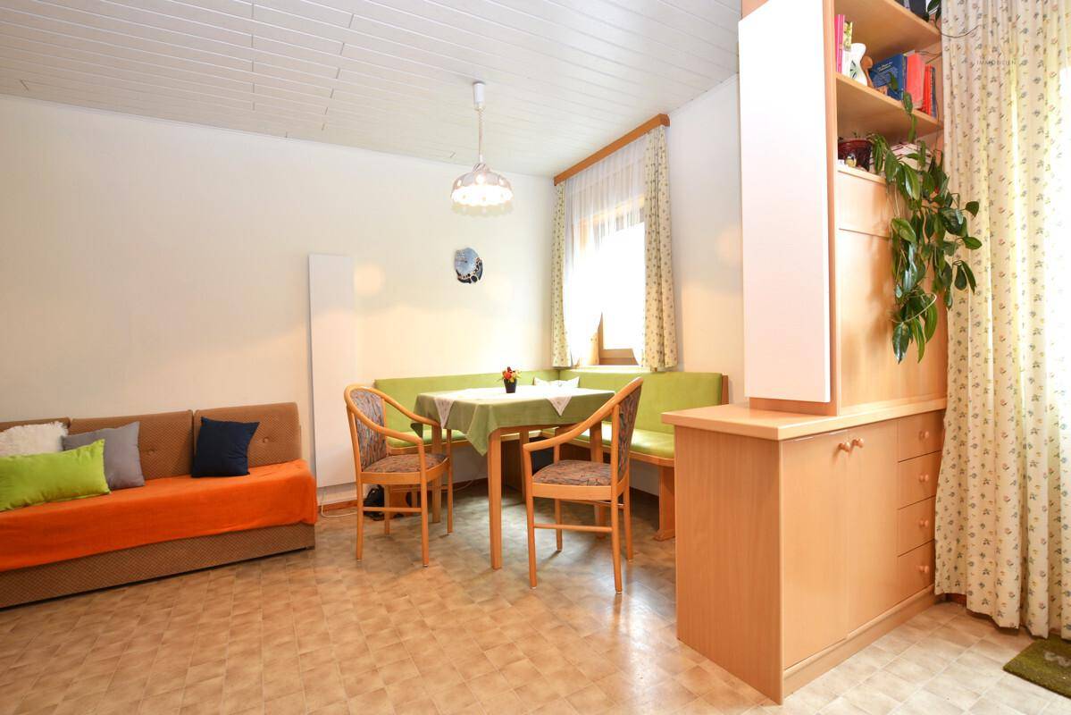 Kombinierter Wohn- und Essbereich mit Eckbank, Sofa und Holzdecke.
