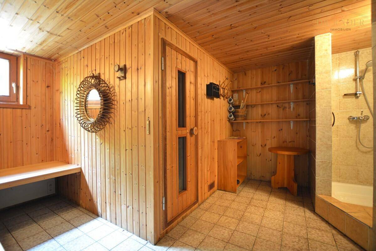 Entspannender Saunabereich mit Holzverkleidung, Sitzbank und integrierter Dusche.