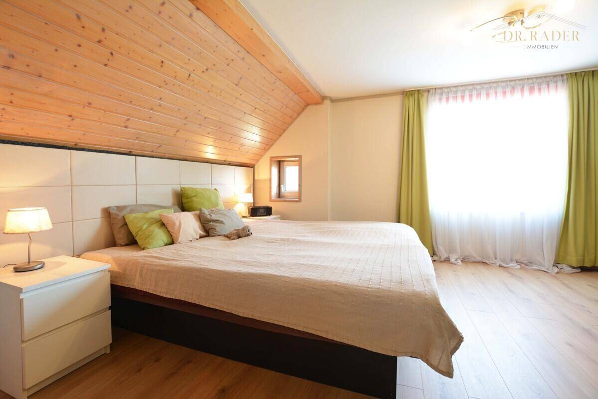 Helles Schlafzimmer mit Holzboden, Dachschräge und sichtbarer Holzdecke.