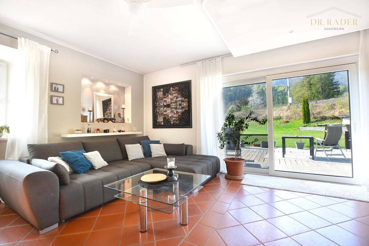 Helles Wohnzimmer mit Terrakottafliesen, großem Sofa und Zugang zur Terrasse.