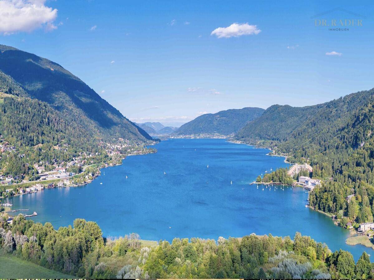 Atemberaubende Luftaufnahme eines großen Sees, umgeben von grünen Bergen und Siedlungen.