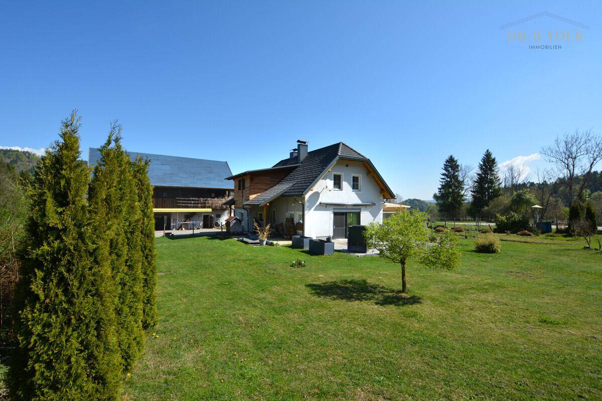 Freistehendes Haus mit großem Garten und angrenzendem Waldgebiet unter blauem Himmel.