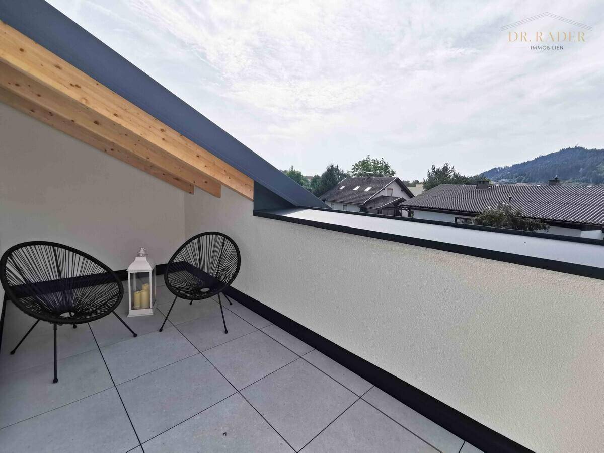 Kleiner Balkon mit zwei modernen Stühlen und Blick auf die umliegende Landschaft.