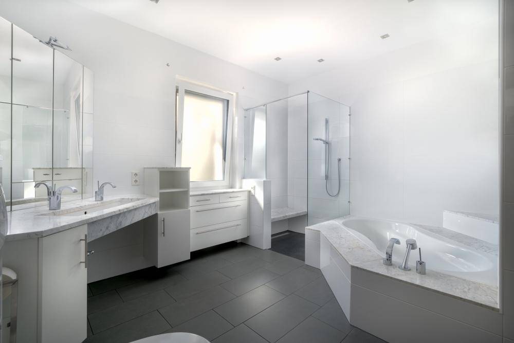 Geräumiges, modernes Badezimmer in Weiß mit Doppelwaschbecken, großer Dusche und Badewanne.