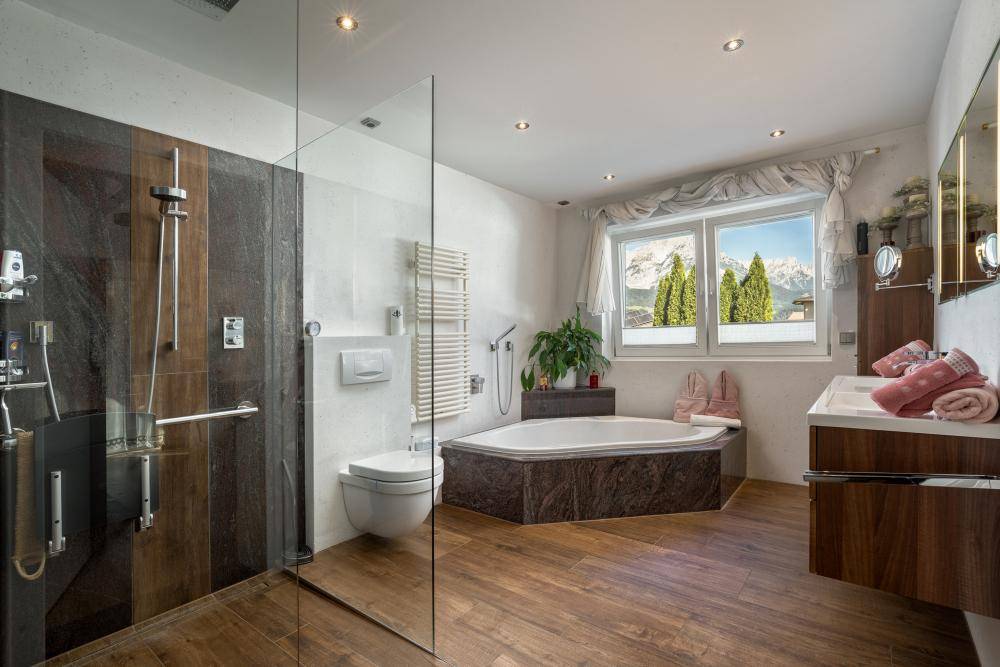 Modernes Badezimmer mit begehbarer Dusche, Eckbadewanne und Doppelwaschbecken mit Bergblick.
