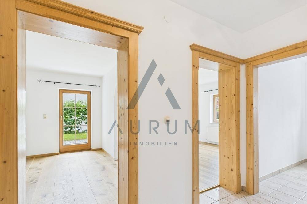 Heller Flur mit Holztürrahmen und Zugang zu weiteren Räumen sowie zum Gartenbereich.