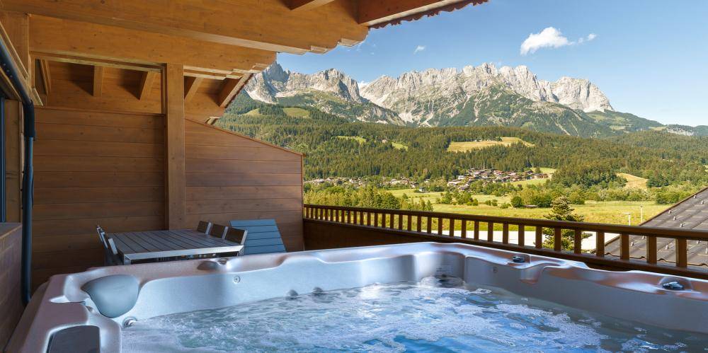 Großer Balkon mit Whirlpool und atemberaubendem Panoramablick auf die majestätischen Berge.
