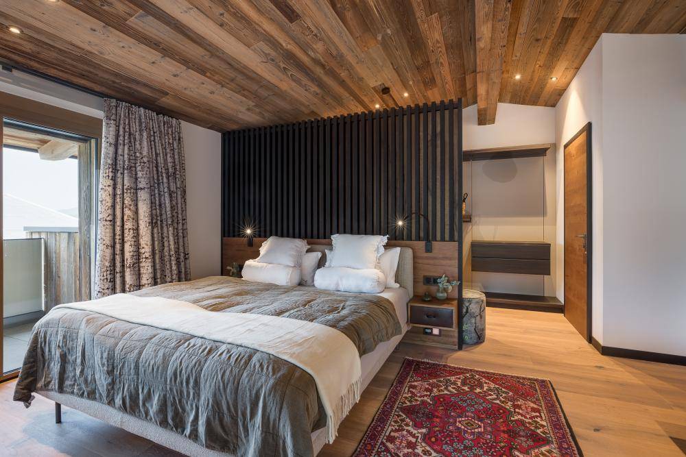 Stilvolles Schlafzimmer mit Holzbalkendecke, Doppelbett und integriertem Kleiderschrankbereich.