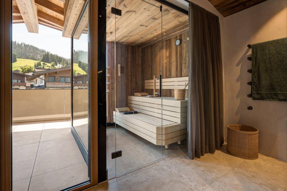Moderne Sauna in einem Badezimmer mit Glasfront und direktem Zugang zu einem Balkon.