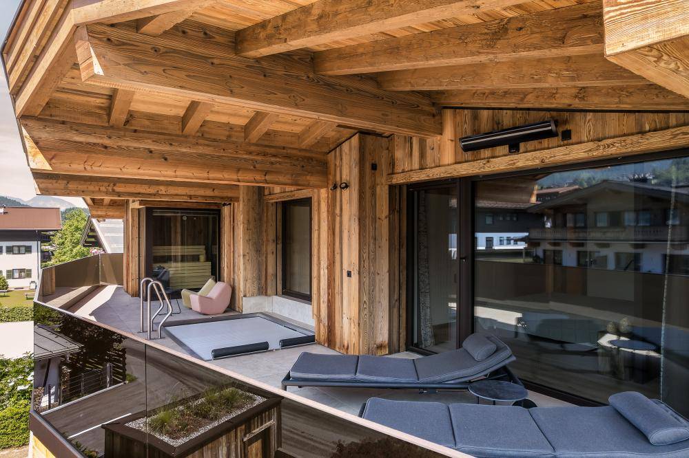 Großer Balkon mit Liegestühlen, Whirlpool und Holzelementen für entspannte Stunden.