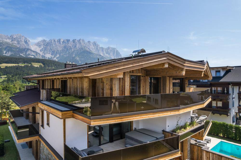 Moderne Architektur mit Holzfassade, großzügigen Balkonen und Whirlpool mit Bergblick.
