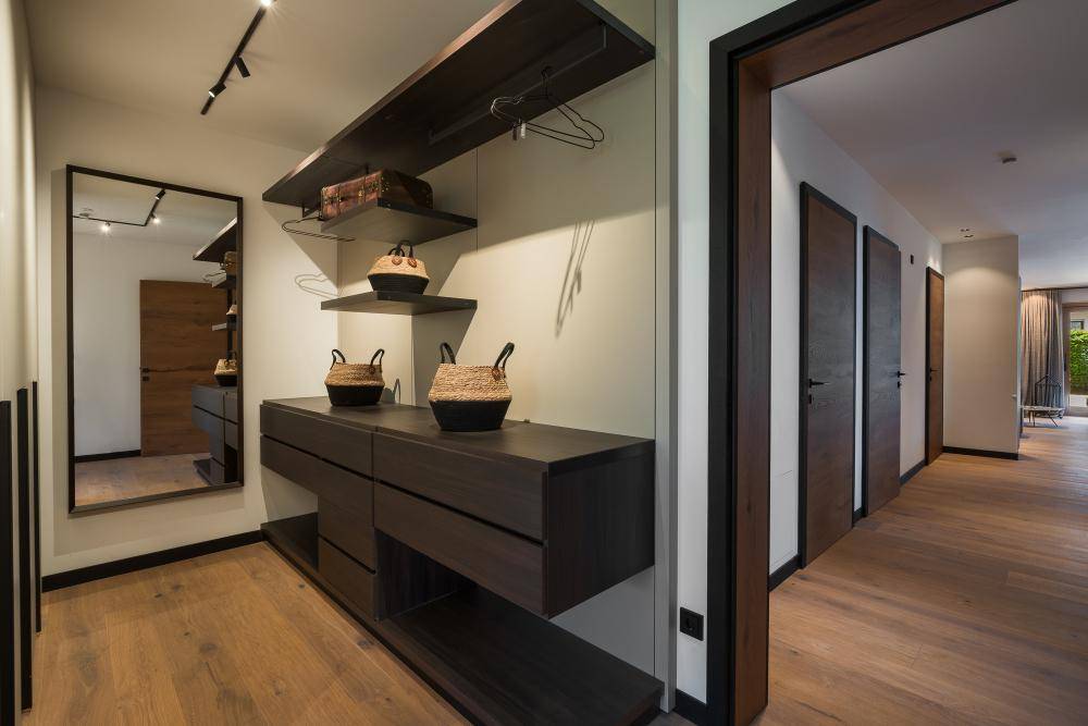 Heller Flur mit Holzboden, modernem Möbelstück und großem Spiegel.