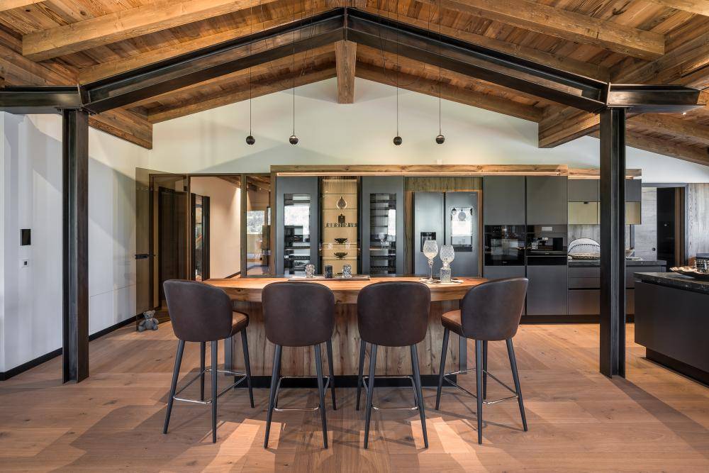Moderne Küche mit Kücheninsel, Frühstücksbar und integrierten Geräten unter Holzbalkendecke.