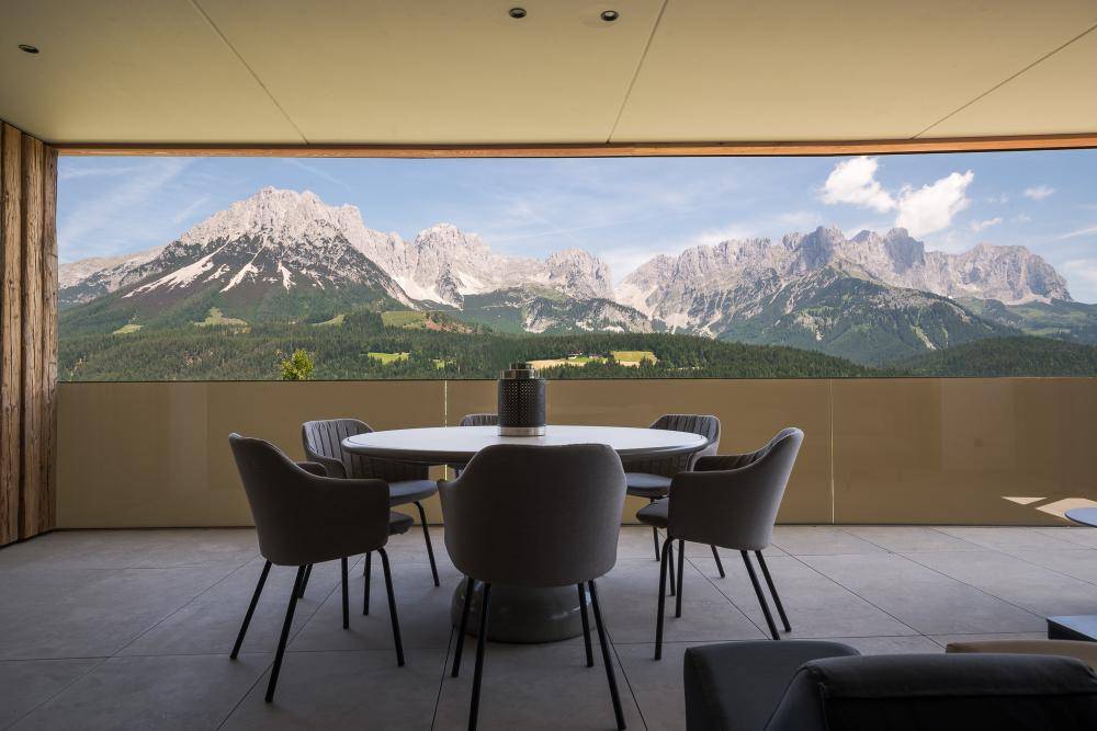 Geräumige Terrasse mit Esstisch und Stühlen, umgeben von einem atemberaubenden Bergblick.