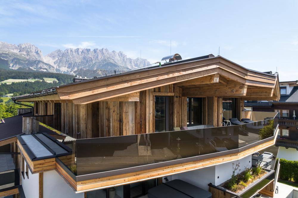 Chalet-Architektur mit Holzfassade, großzügigen Balkonen und traditionellem Dach.