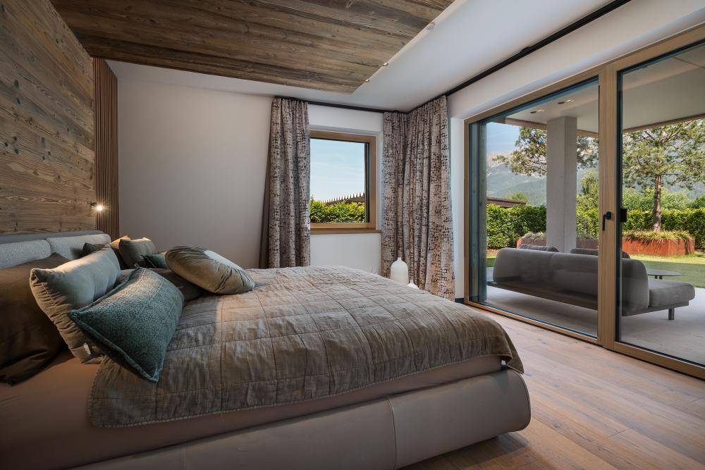 Gemütliches Schlafzimmer mit Holzwand, großem Bett und Zugang zum Garten.