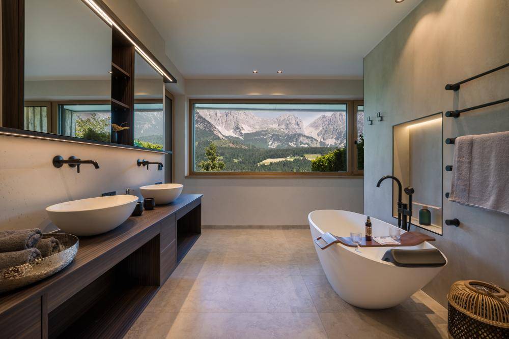 Luxuriöses Badezimmer mit Doppelwaschbecken, freistehender Badewanne und Bergblick.