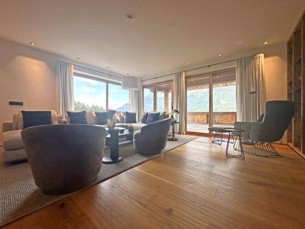 Helles Wohnzimmer mit Holzboden, großen Fenstern und Bergblick.
