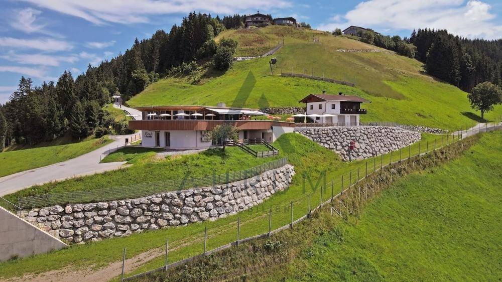 Panoramablick auf den Gebäudekomplex auf einem grünen Hügel mit Steinmauern und umliegender Natur.