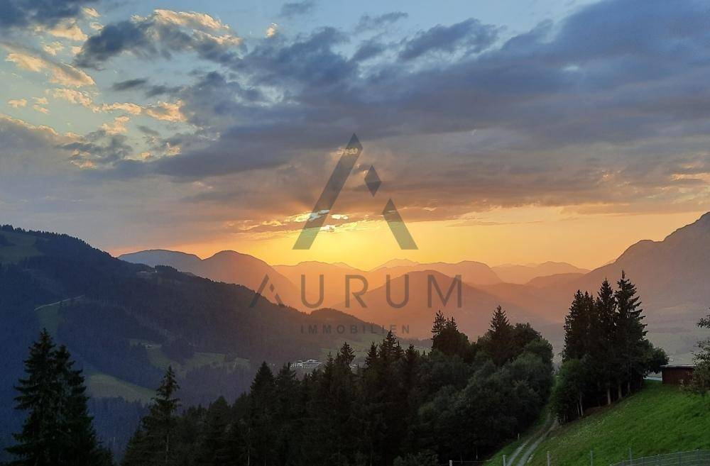 Spektakulärer Sonnenuntergang über einer malerischen Berglandschaft mit sanften Hügeln und dichten Wäldern.