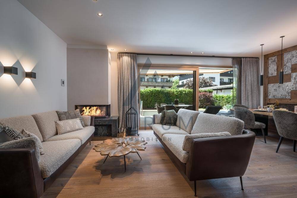 Gemütlicher Wohn-Essbereich mit modernem Kamin, Holzboden und Zugang zur Terrasse.