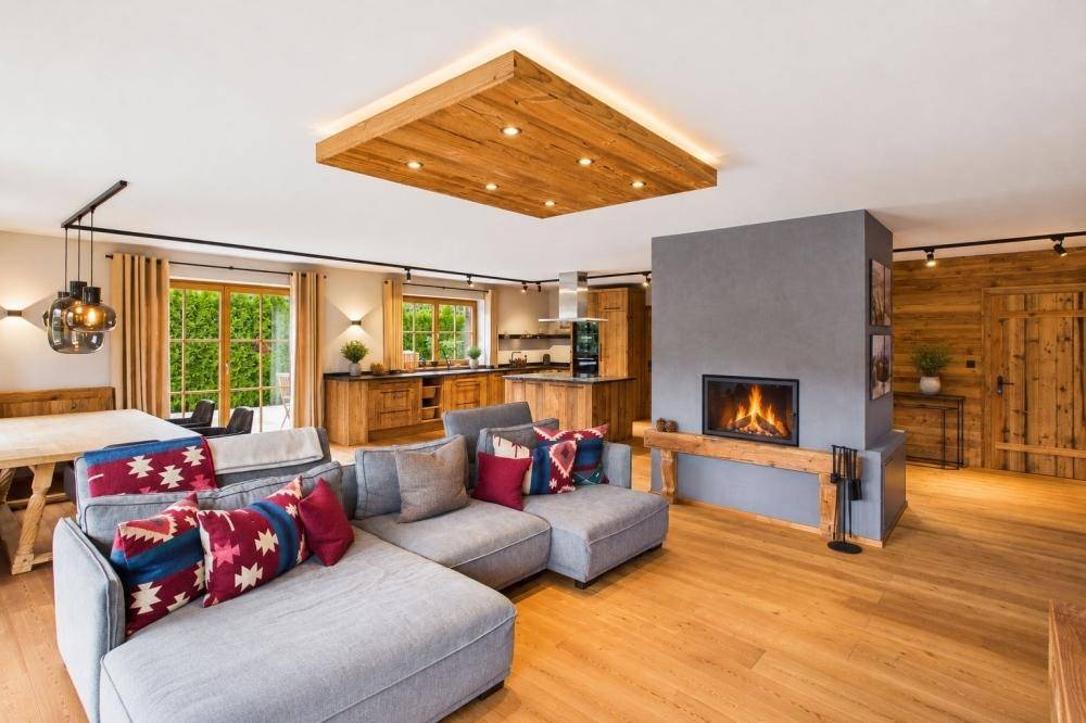 Gemütlicher offener Wohn-Essbereich mit Kamin, Holzboden und integrierter Holzküche.