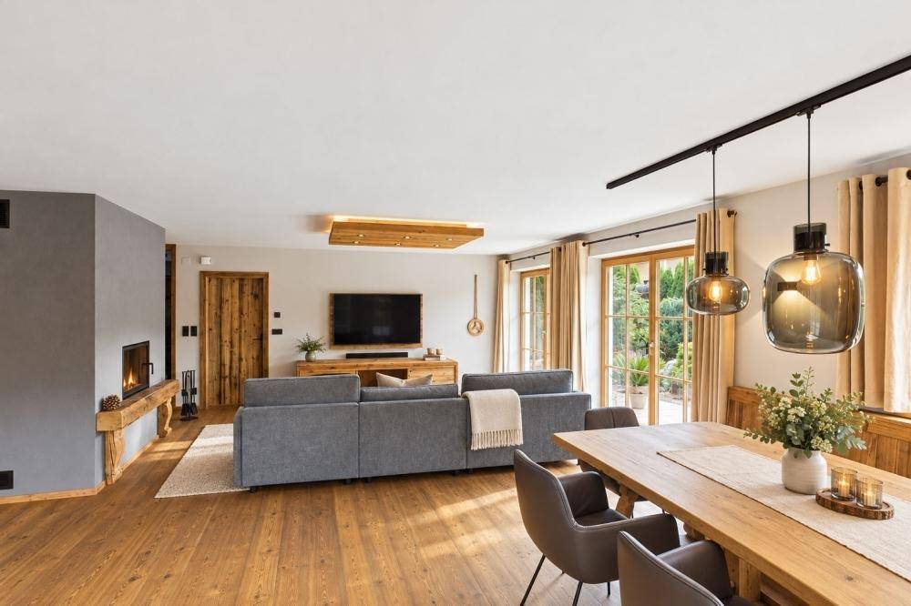 Heller Wohn- und Essbereich mit Holzboden, modernem Kamin und Zugang zum Garten.