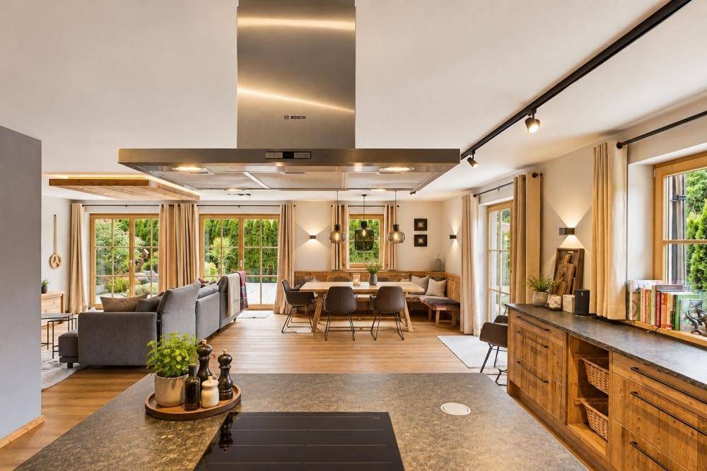 Offene Küche mit Kochinsel und Essbereich, verbunden mit dem Wohnzimmer und Gartenzugang.