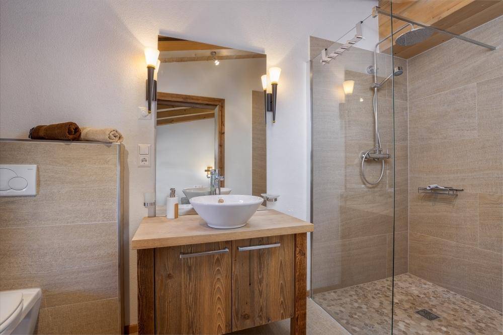 Modernes Badezimmer mit begehbarer Dusche, Holzwaschtisch und hellen Fliesen.
