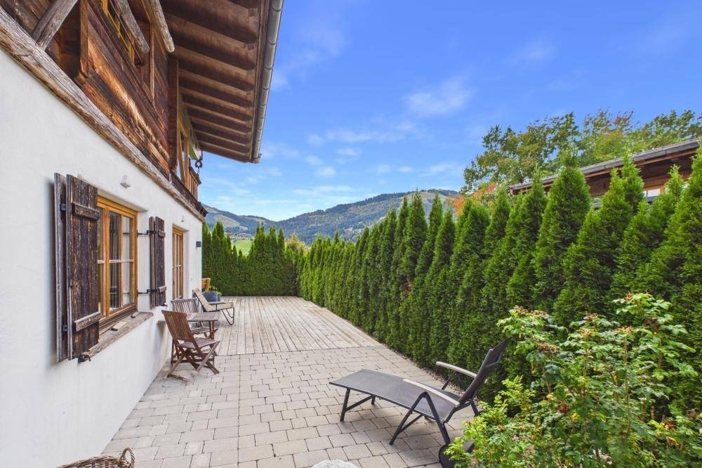 Gepflasterte Terrasse mit Liegestuhl und Blick auf die umliegende Berglandschaft.