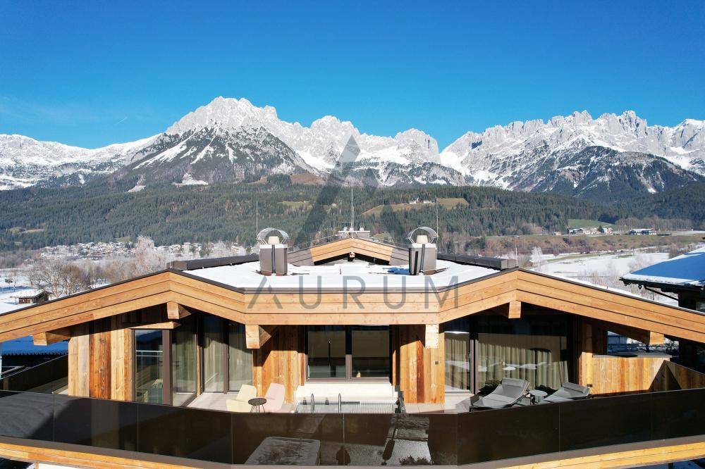Geräumige Dachterrasse mit Liegestühlen und atemberaubendem Panoramablick auf die verschneiten Berge.