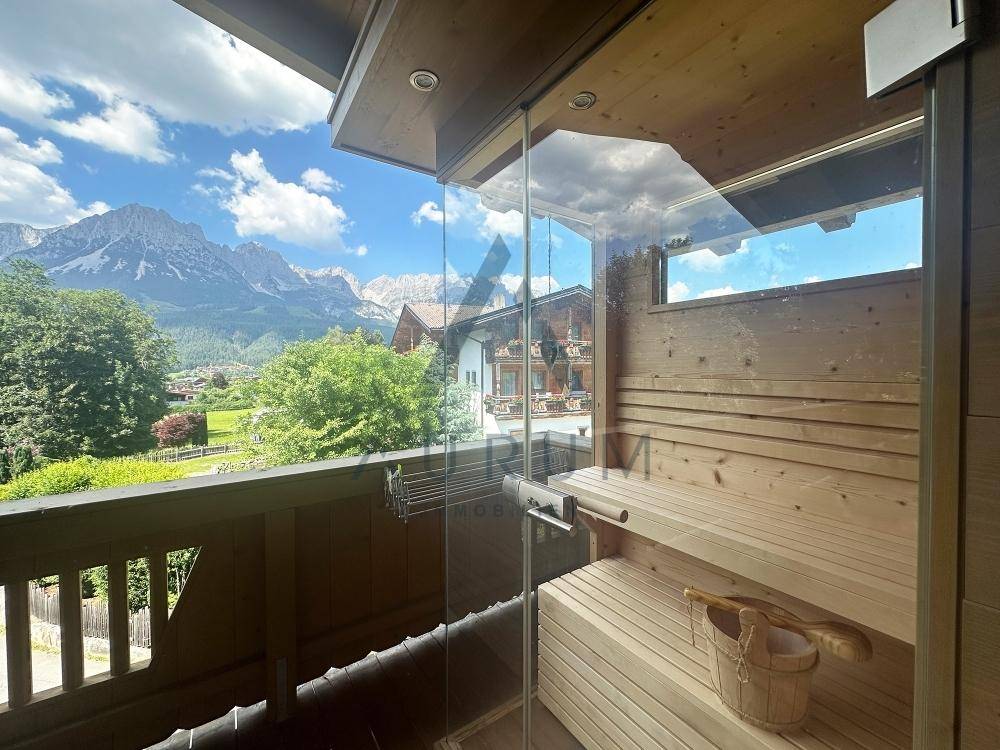 Holzvertäfelte Sauna mit Glasfront und direktem Blick auf die beeindruckende Bergkulisse.